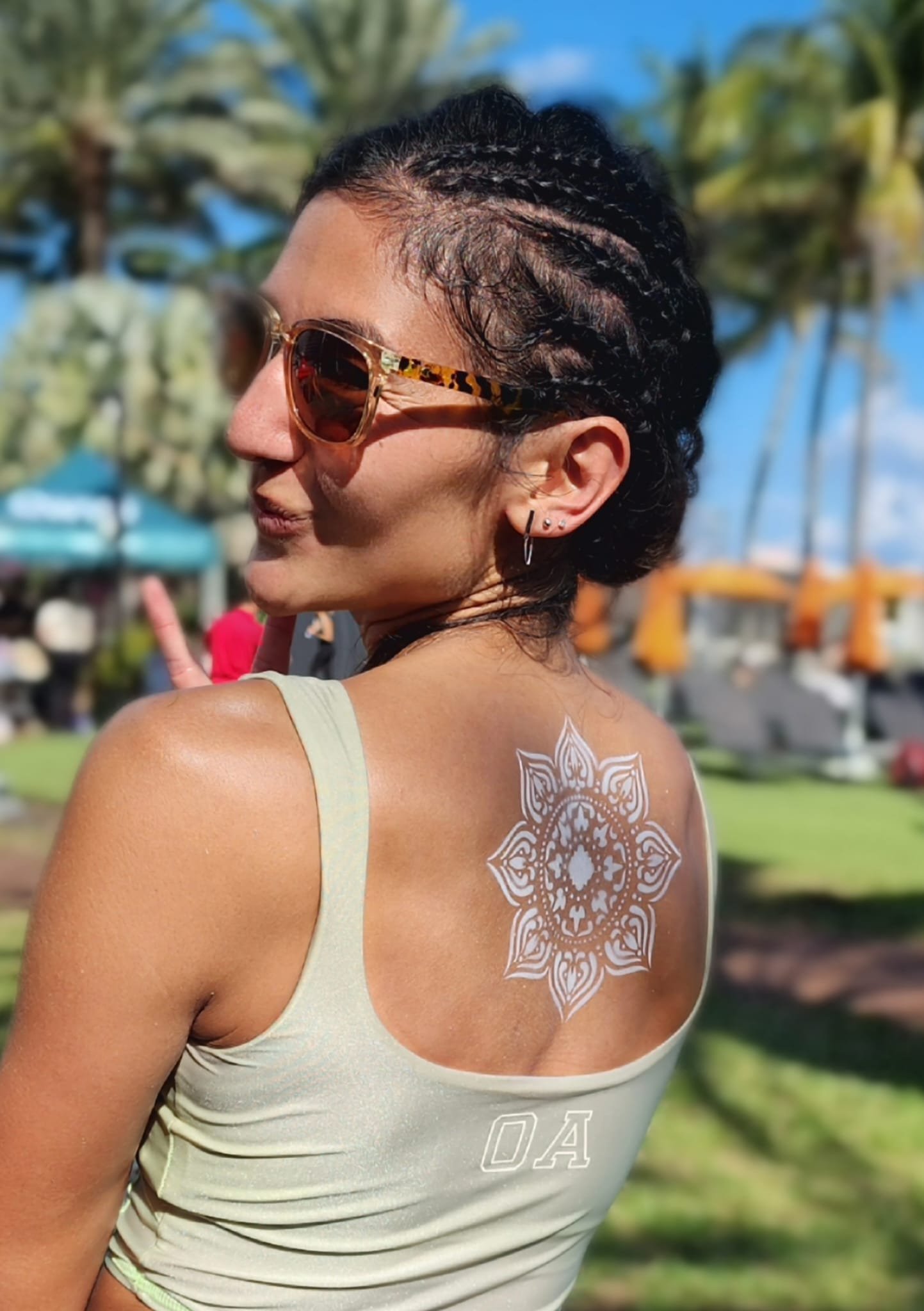 White boho mandala painted on the shoulder blade at an outdoor festival