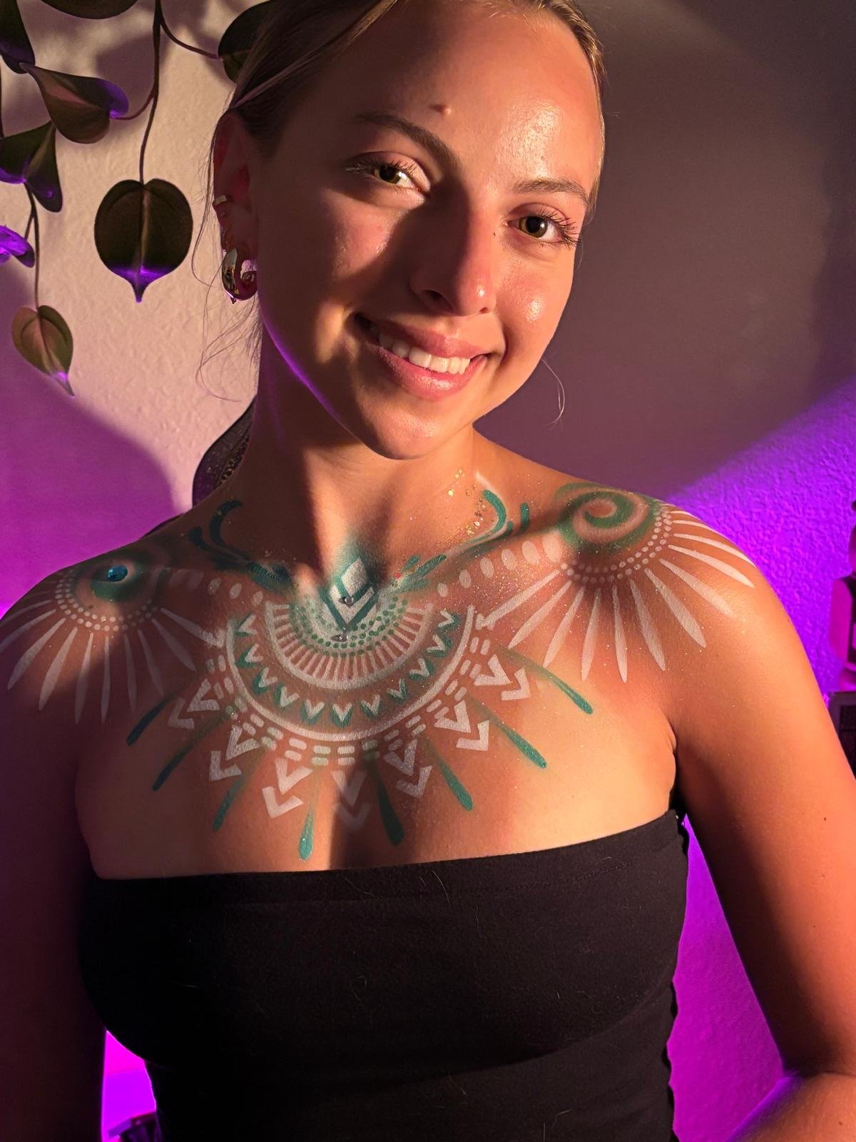 Teal and white festival body paint across the chest and shoulder